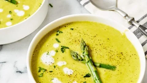 Delicious creamy asparagus soup served in a bowl with fresh asparagus garnishing